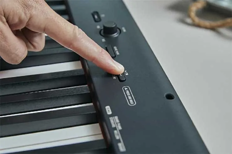 Close-up of the Casio CDP-S160 panel: a finger on a button beside the volume dial