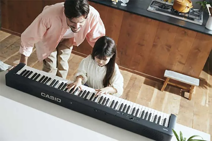 A parent and child playing the Casio CDP-S160 side by side, seen from above