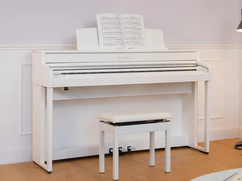 A white Kawai CA501 digital piano with its bench in a living room