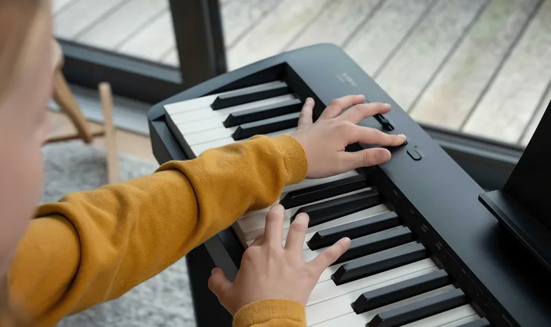 Hands playing the Kawai ES60's keys, seen from the side