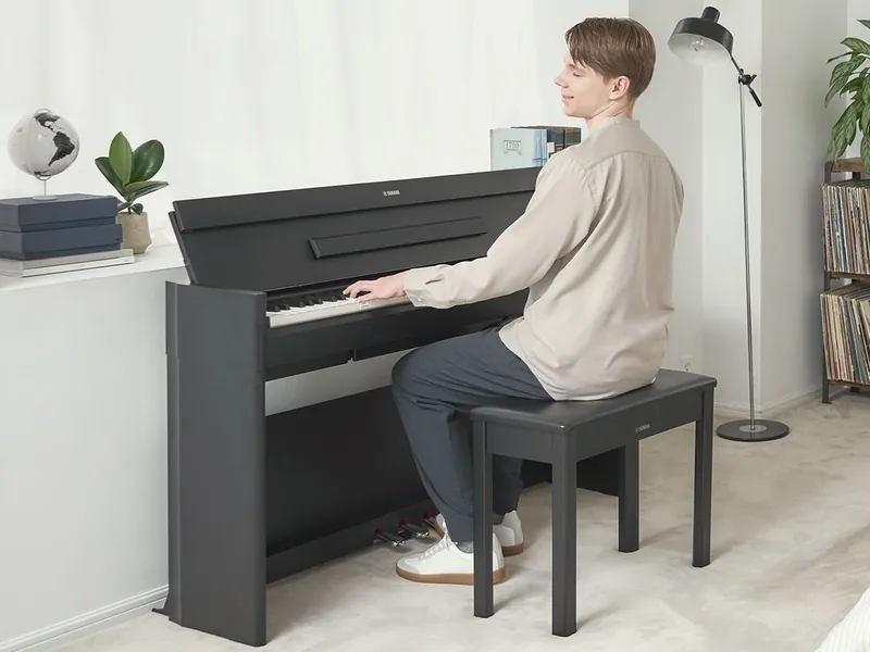 A young man playing a Yamaha YDP-S56 digital piano at home